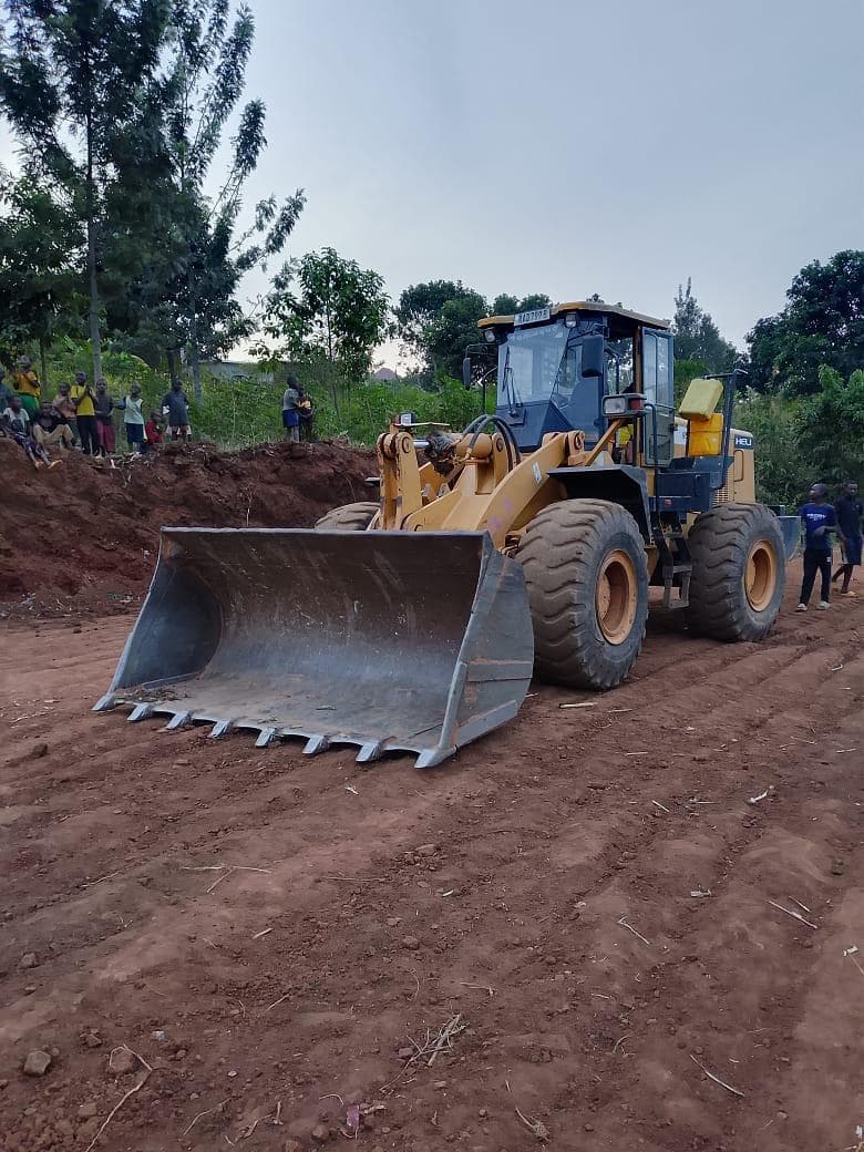 Wheel loader with a toothed bucket levelling red soil at dusk