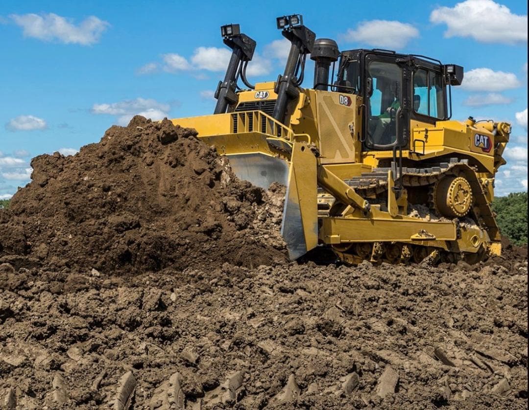 Caterpillar D8 dozer pushing a pile of dark soil