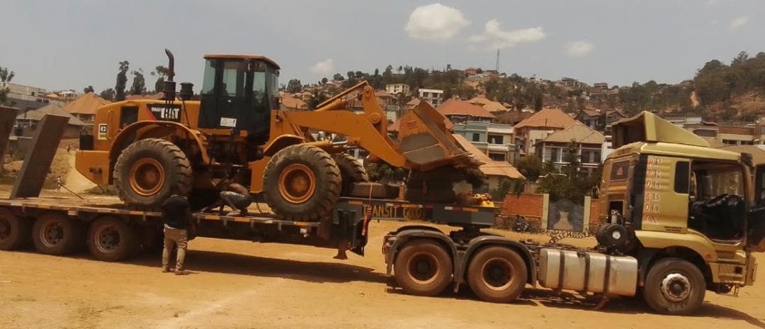 Lowbed trailer carrying a Caterpillar 966 wheel loader through Kigali